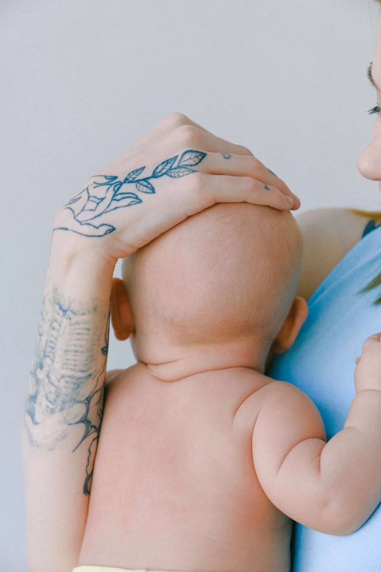 Mother with a tattoo holding her newborn