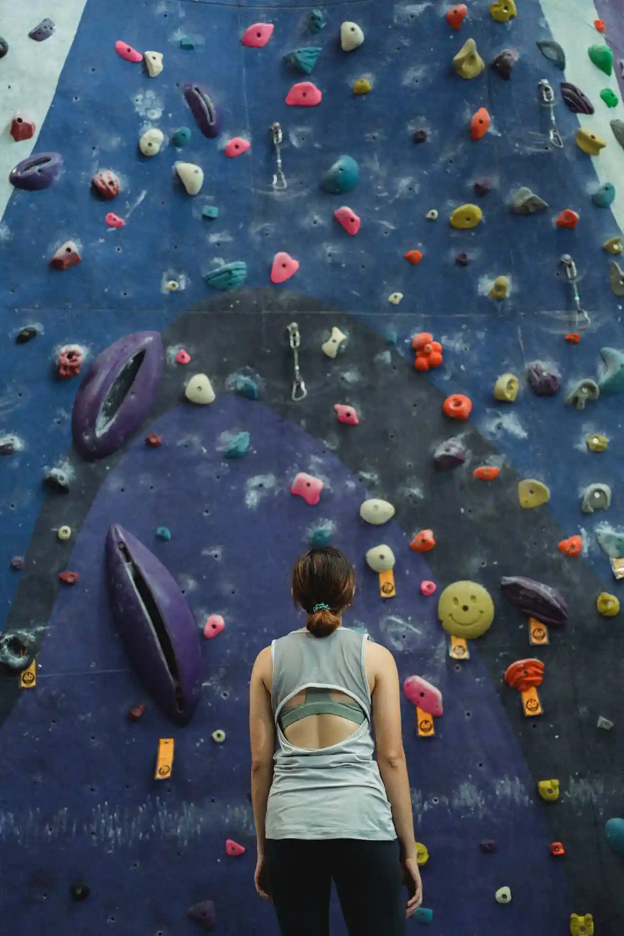 A woman staring up at a rock climbing wall